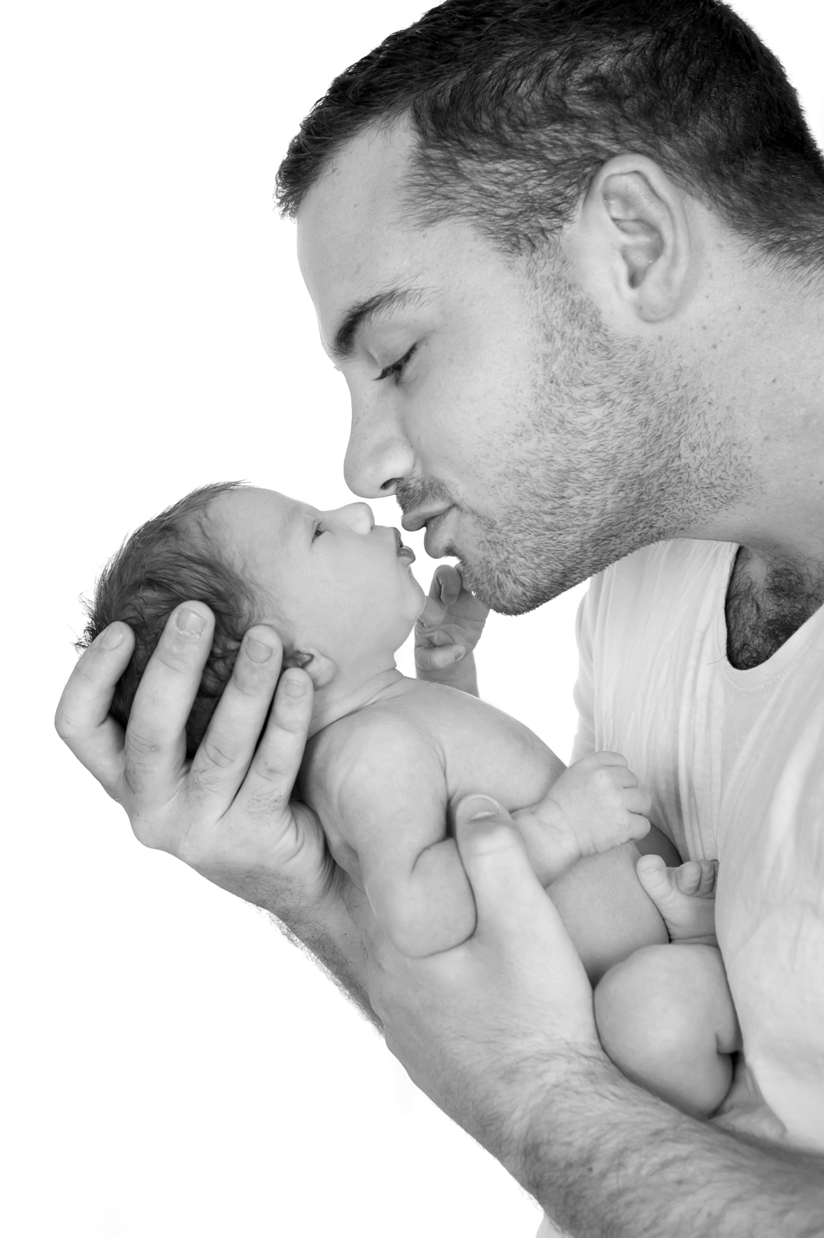 Father kissing newborn black and white